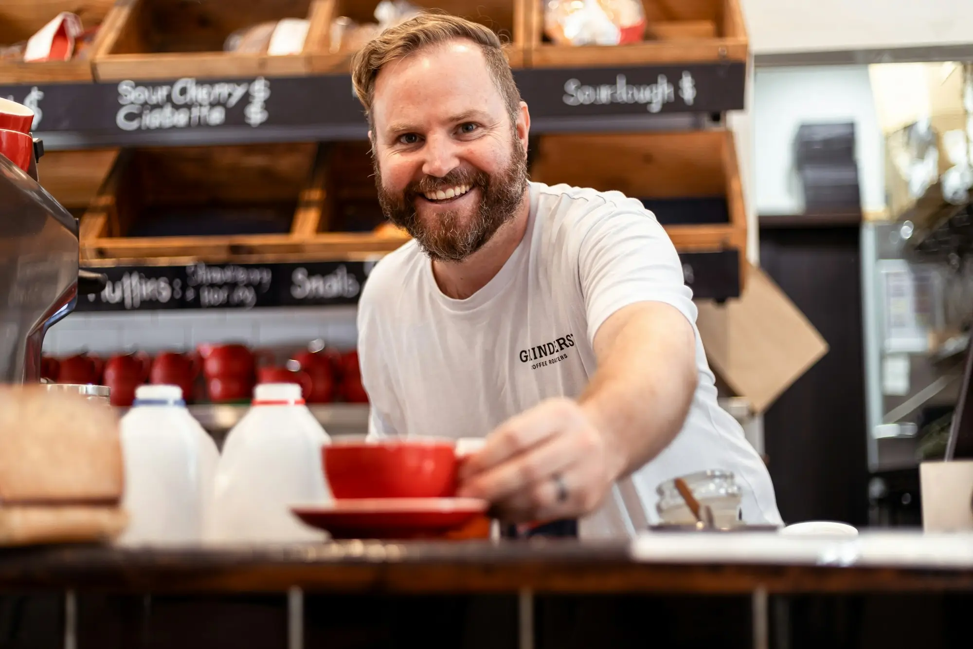 Smiling cafe owner serving a coffee across the counter in Sydney