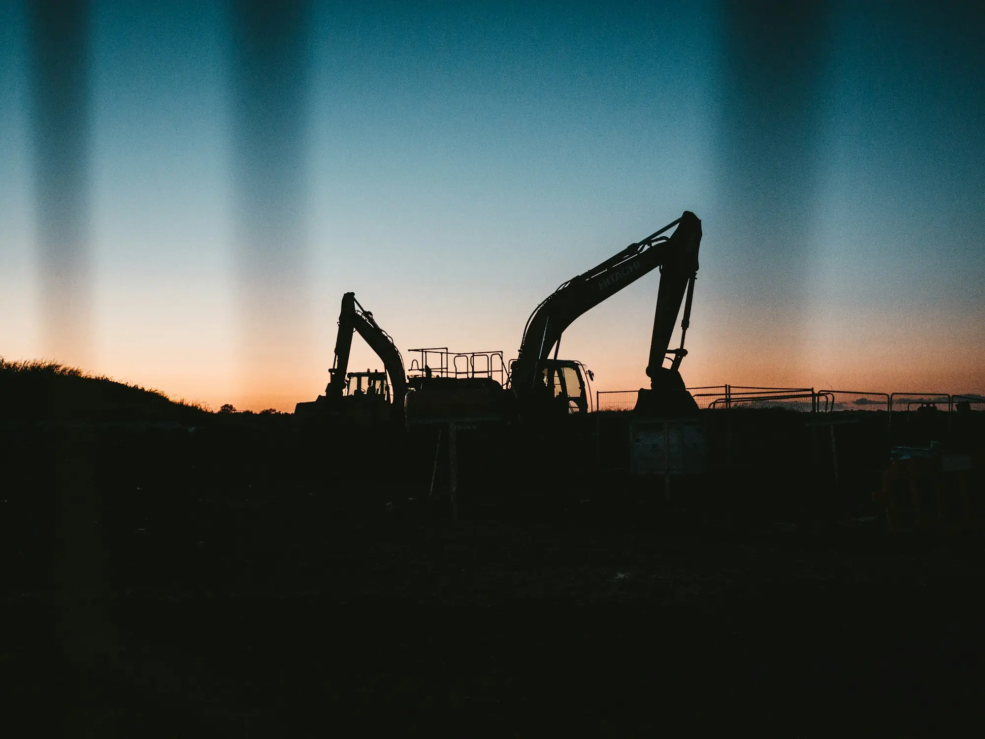 Two excavators silhouetted against the sunrise on an earthmoving site near Geelong