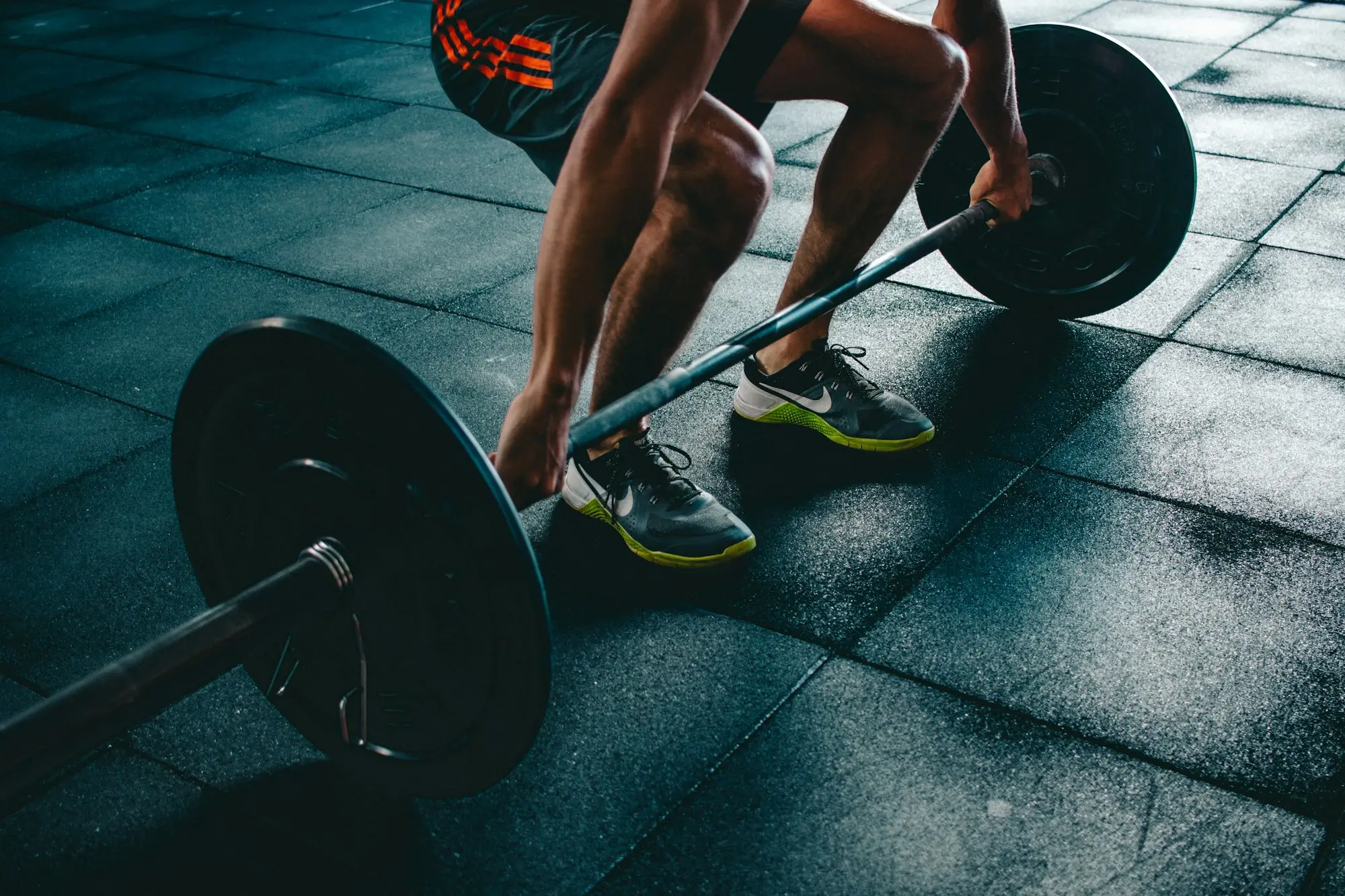 Gym member lifting a loaded barbell on a rubber gym floor