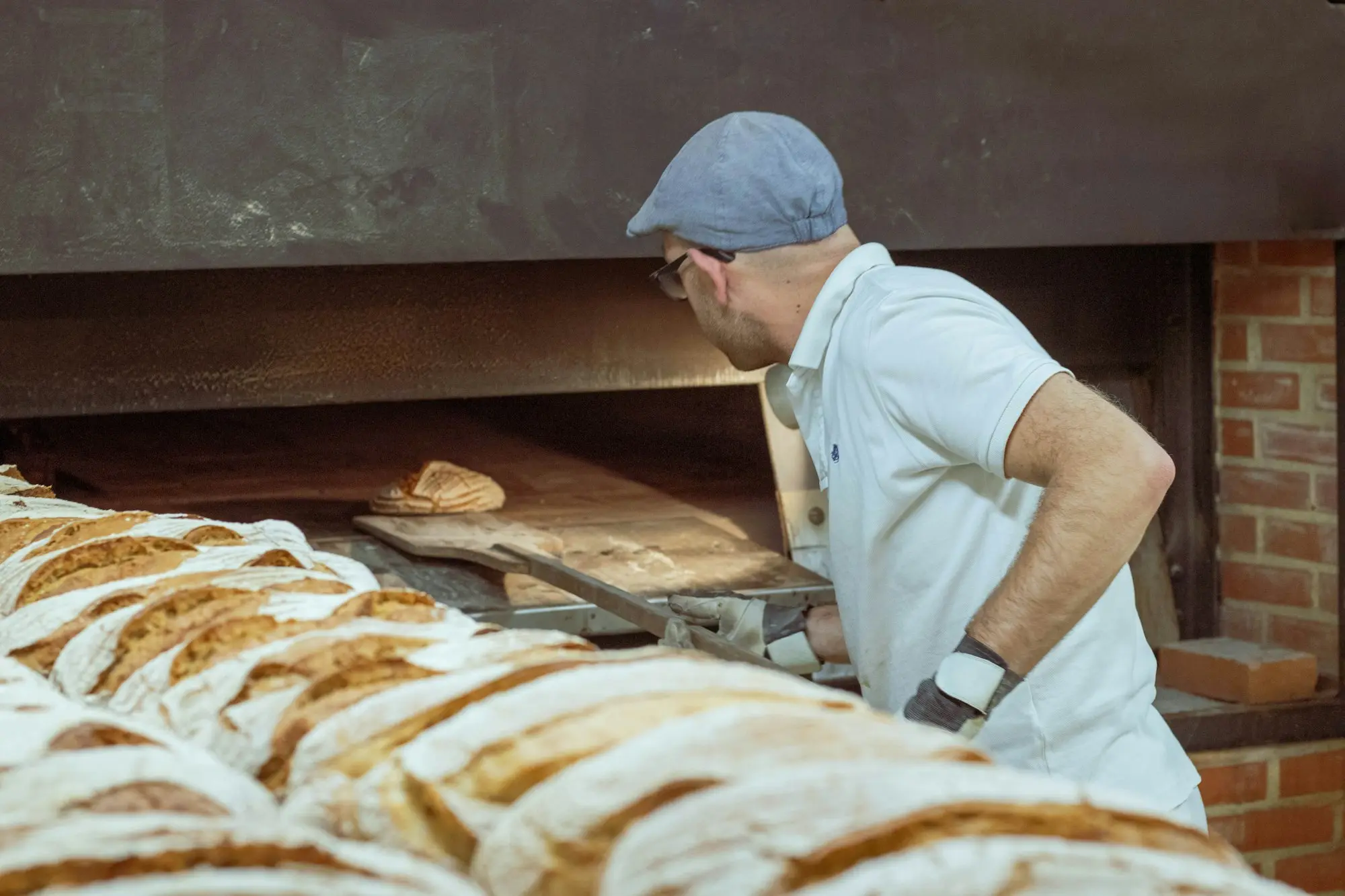 Baker loading bread into a wood-fired oven early in the morning