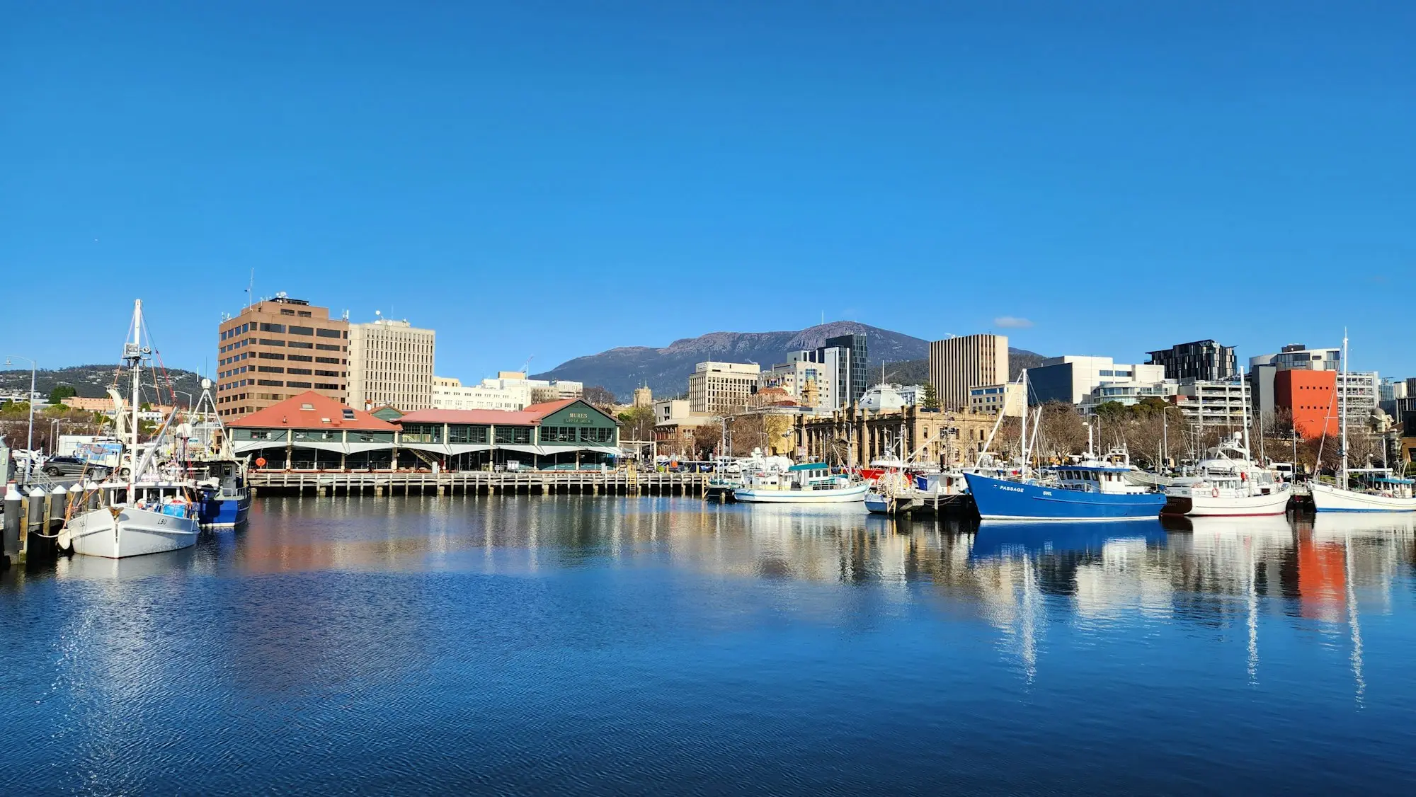 Boats moored on the Hobart waterfront with kunanyi Mount Wellington behind