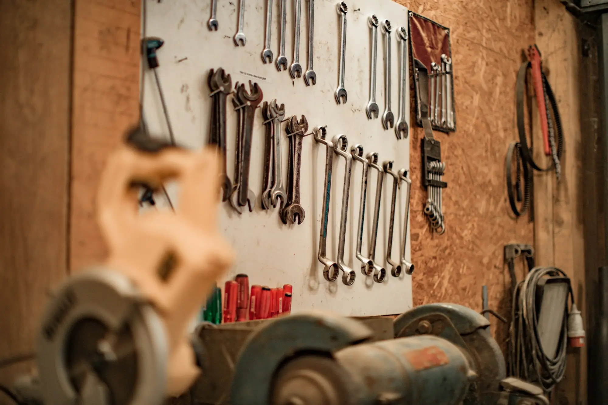 Spanners and tools hanging on the wall of a busy mechanic workshop