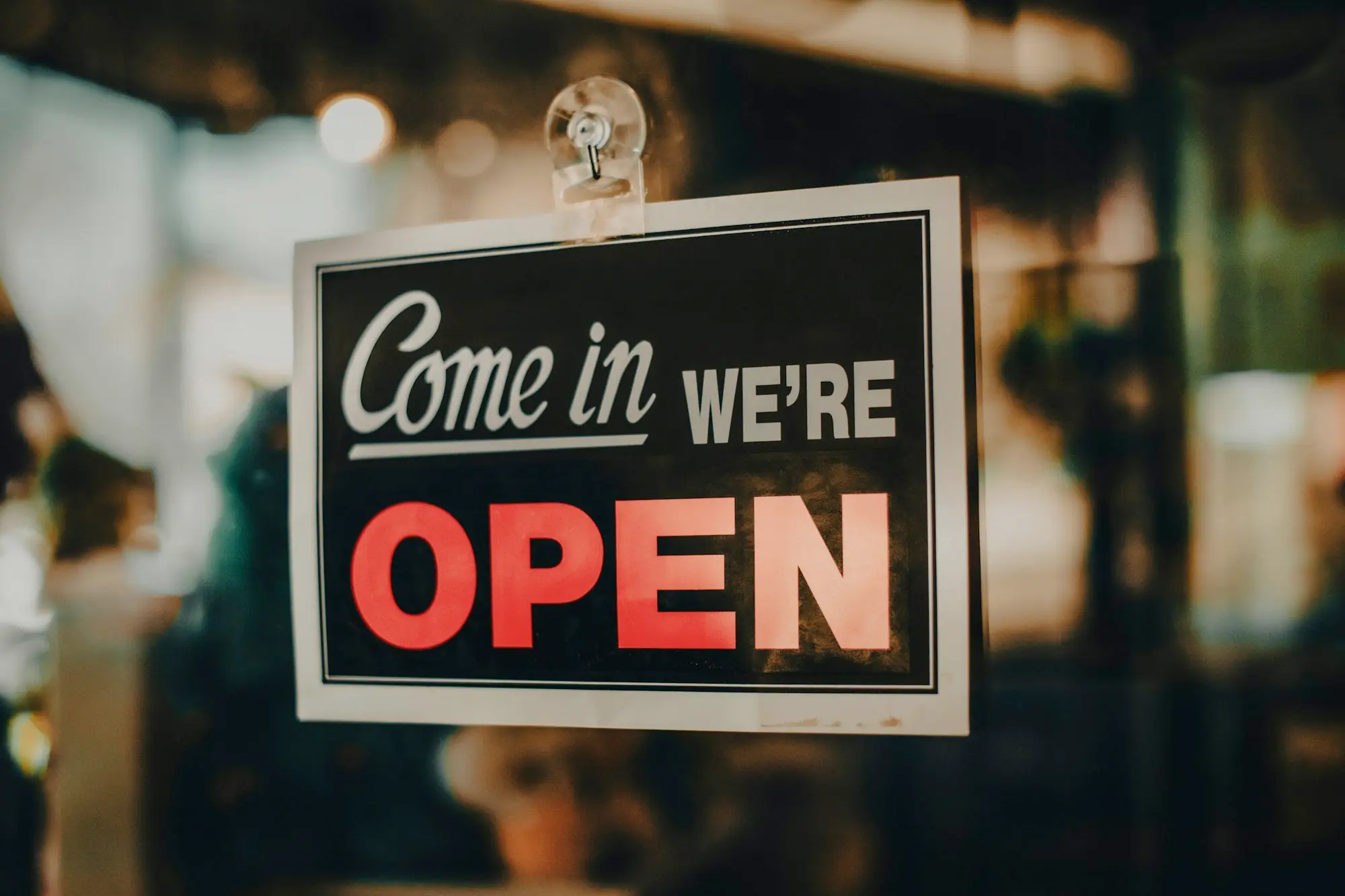 Come in we're open sign hanging in a small shop doorway
