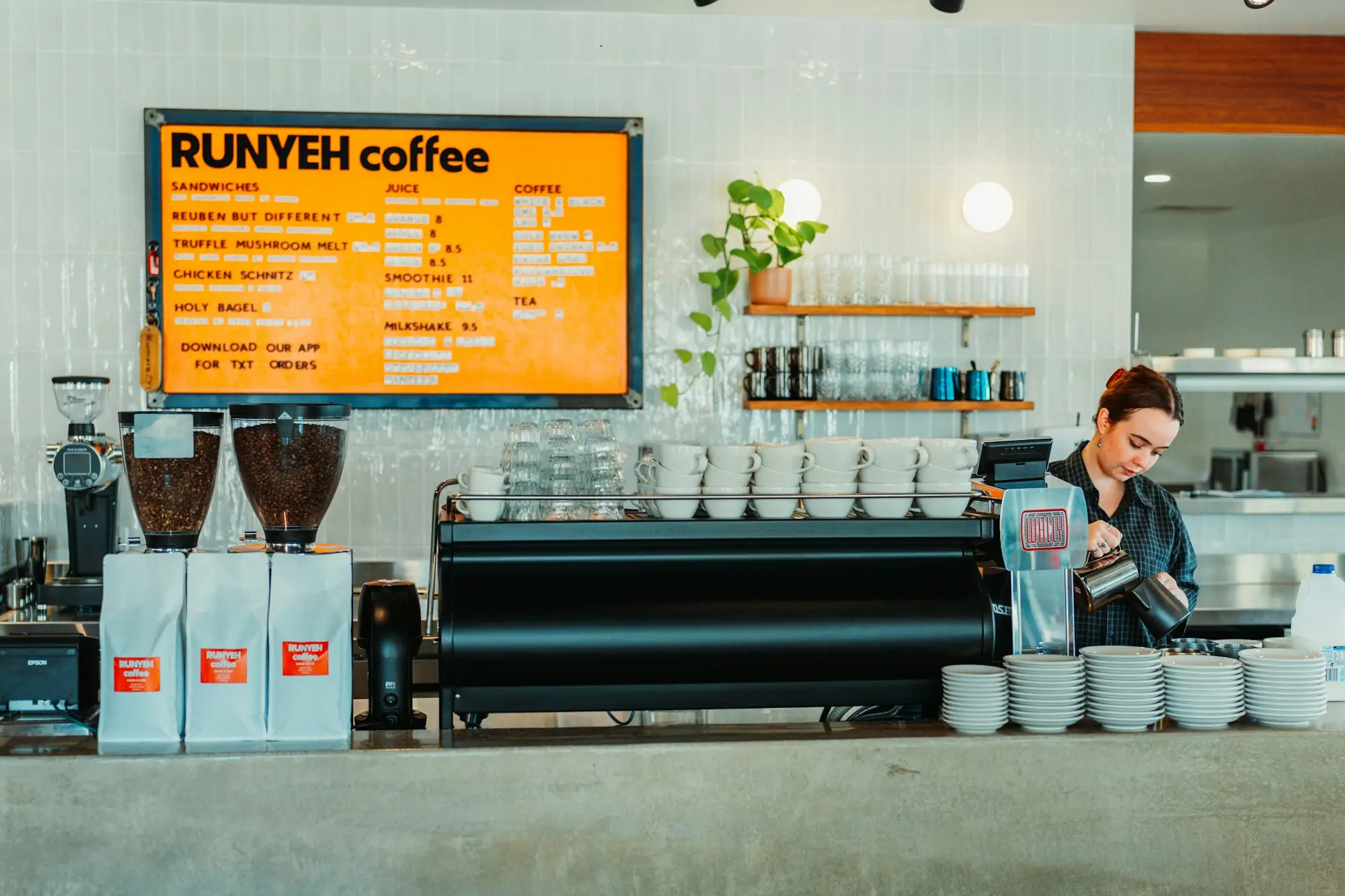 Barista pouring milk at the espresso machine in a Perth coffee shop