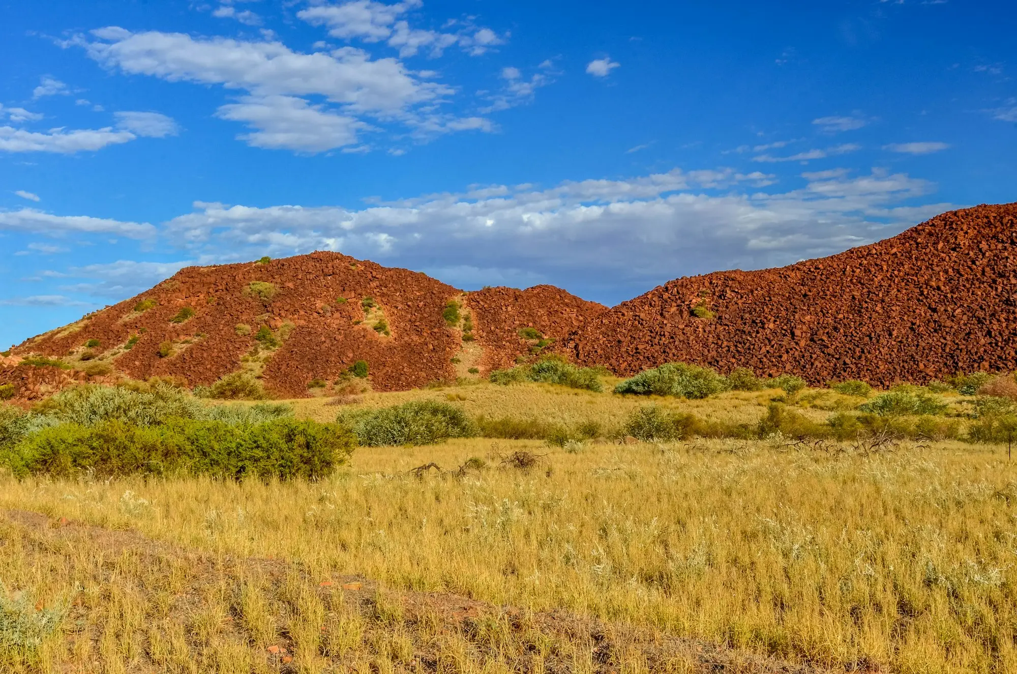 Red Pilbara hills rising above golden spinifex in Western Australia