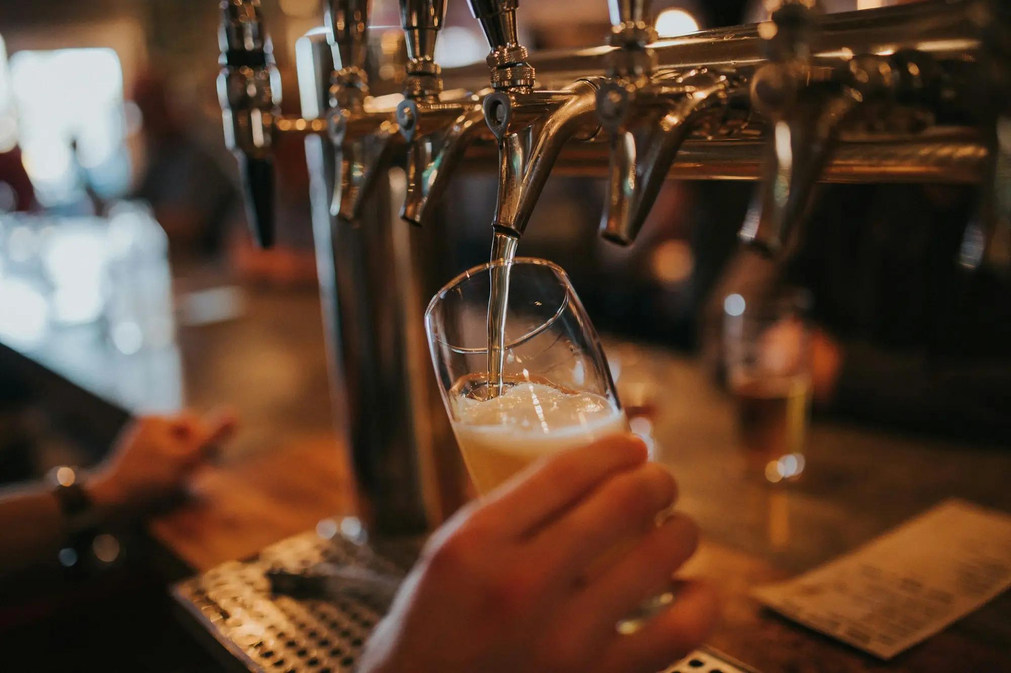 Bartender pouring a beer from the taps at a pub front bar