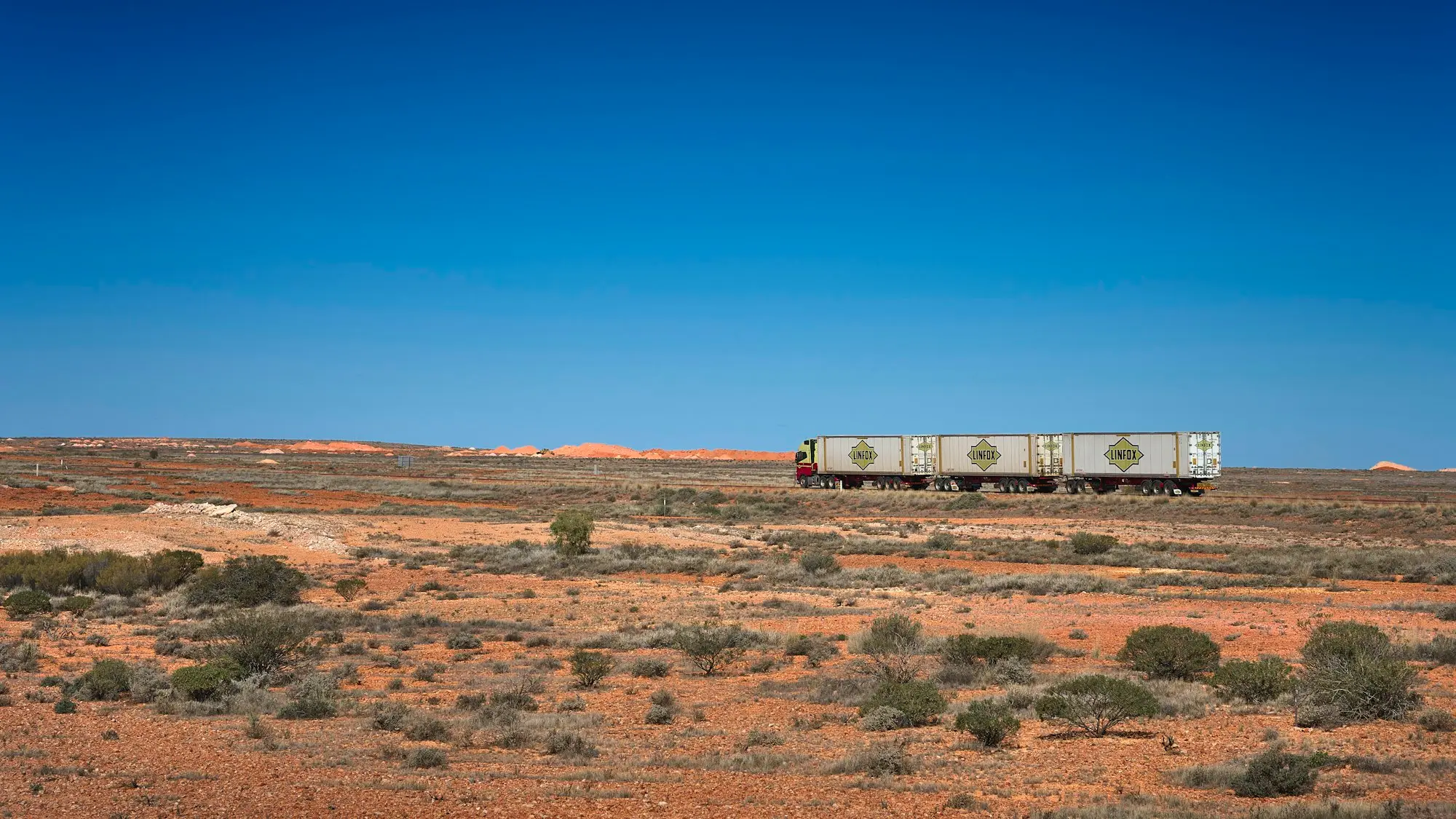 Road train crossing red outback country on the Stuart Highway