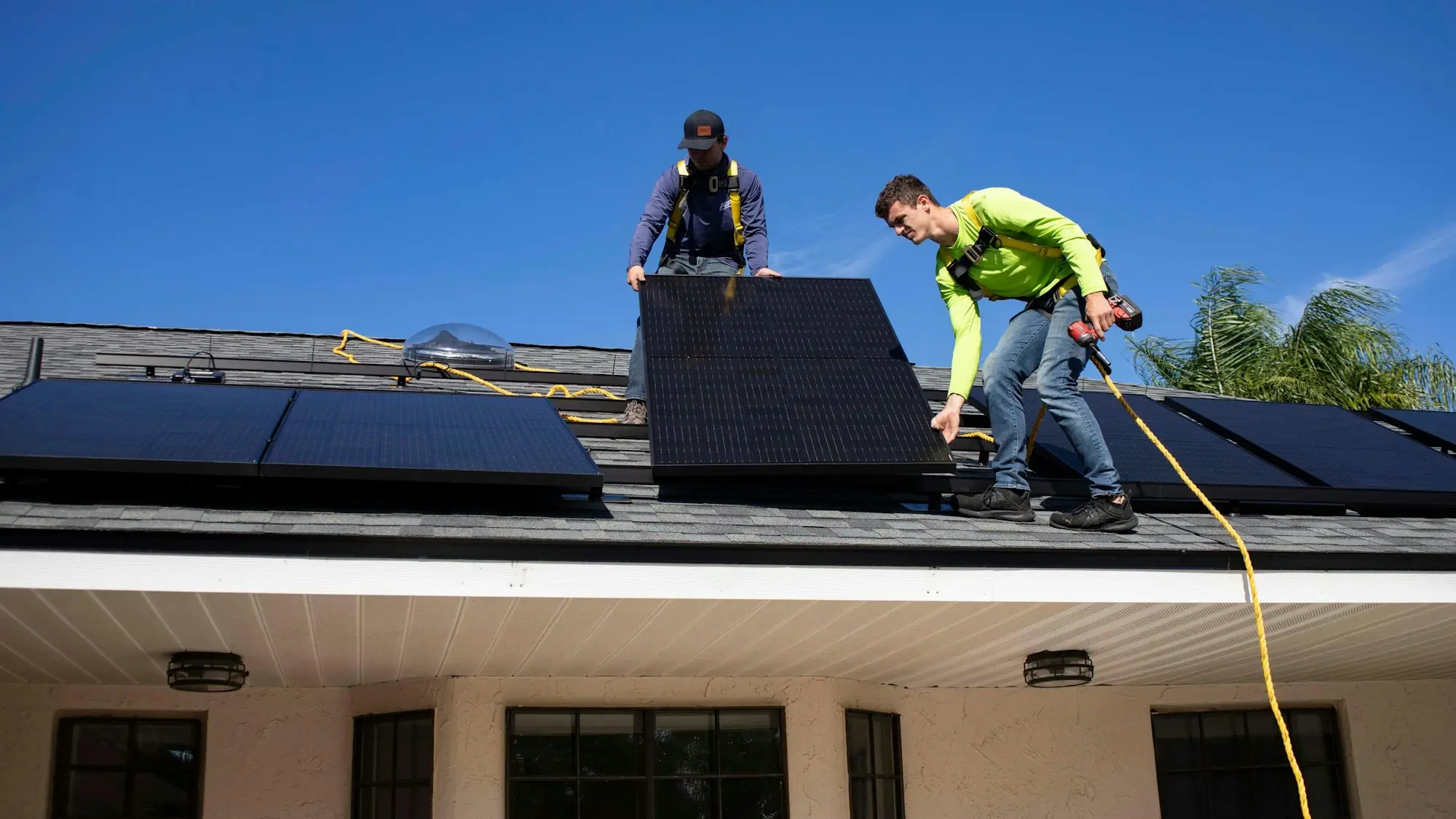 Two installers fitting solar panels on a house roof